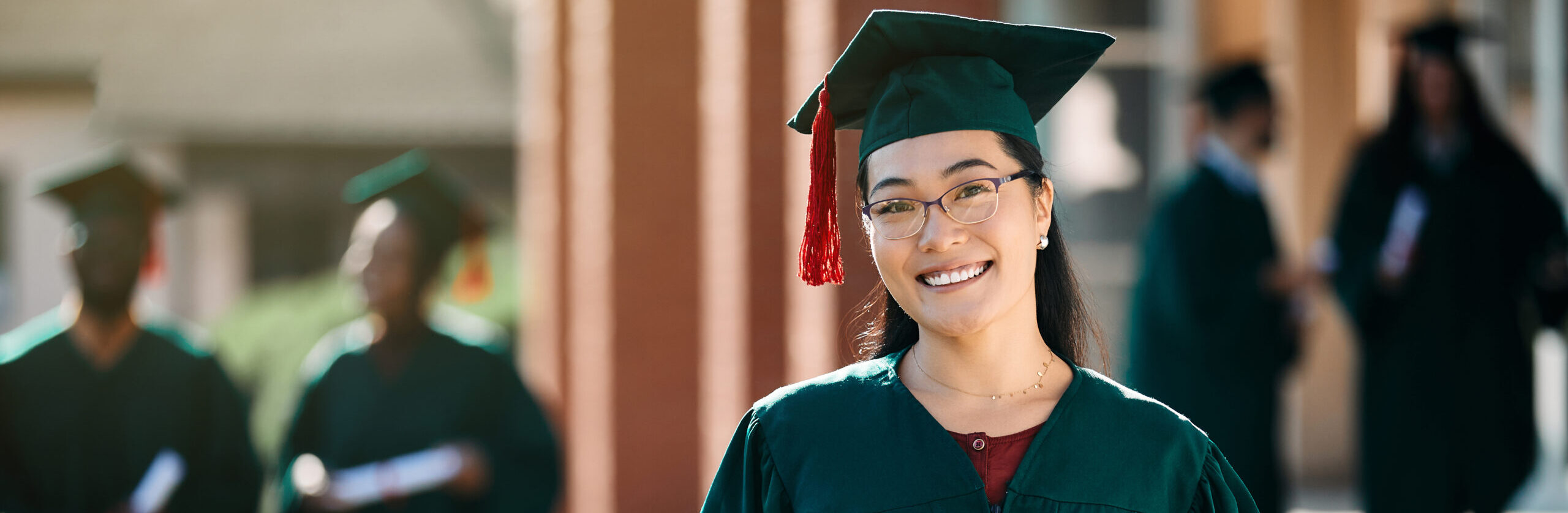 Happy Asian female student with bachelor's degree on her graduation day looking at camera.